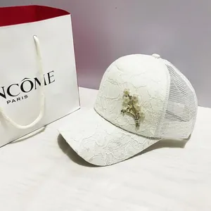 Détail de la casquette de baseball en dentelle blanche avec fleur perlée et filet