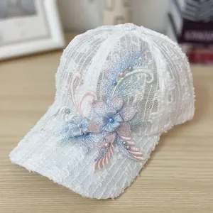 Detail of white mesh lace baseball cap featuring 3D floral embroidery and hand-sewn pearls