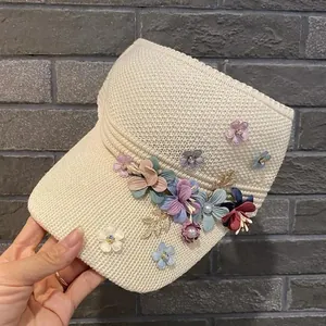 Close-up of knit sun visor with handmade fabric flowers and pearl accents