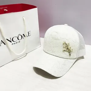 Détail de la casquette de baseball en dentelle blanche avec broche fleur en strass