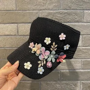 Women's black knitted sun visor hat featuring colorful 3D floral appliques and gold leaf accents