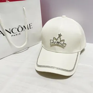 Dettaglio del cappellino bianco con corona di strass e bordo della visiera brillante