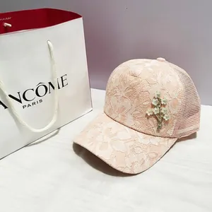 Détail du tissu en dentelle rose sur casquette d'été avec broche fleurie et filet