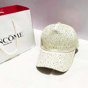 Detailopname van een beige baseballpet met glinsterende strass-steentjes en gebogen klep