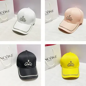 Dettaglio di cappelli da baseball con emblema corona di strass e bordo luccicante