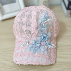 Detail view of pink lace baseball cap with floral embroidery and pearl accents