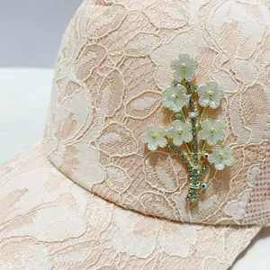 Détail du tissu en dentelle rose et des strass floraux sur cette casquette d'été