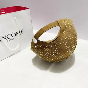 Zijaanzicht van een bruine canvas handtas met zilveren strass-steentjes en metalen gesp