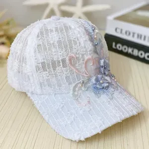 Detailed view of white mesh cap featuring 3D floral embroidery and elegant pearl accents