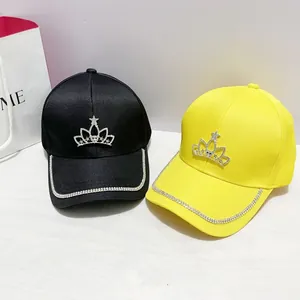 Dettaglio di cappellini da baseball con corona di strass neri e gialli con bordo in cristallo