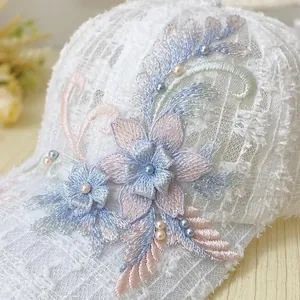 Detailed view of floral embroidery and pearls on a white lace mesh baseball cap