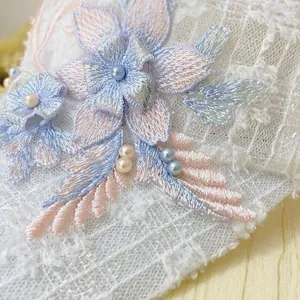 Detail of 3D floral embroidery lace with soft pastel pearls and fine mesh texture