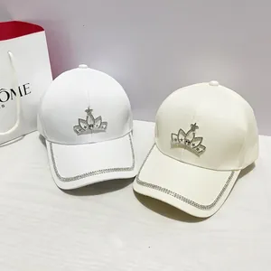 Dettagli di cappellini bianchi e beige con corona di strass e visiera brillante
