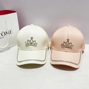 Dettaglio cappellini da baseball con corona di strass in beige e rosa con cristalli