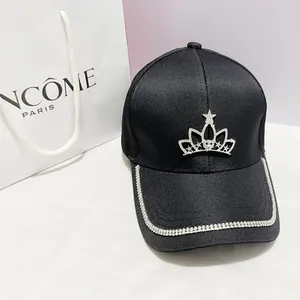 Dettaglio cappellino nero con bordi in strass e stemma a corona in metallo argento