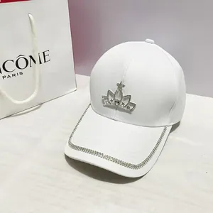 Dettaglio di un cappello da baseball bianco con corona di strass e visiera lucida