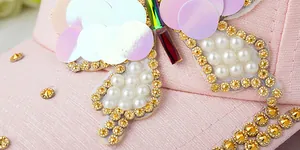Detail of pink baseball cap with sequins, faux pearls, and sparkling rhinestones