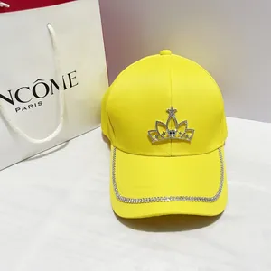 Dettaglio del cappello da baseball giallo con corona di strass e decorazione sulla tesa