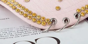 Detail of pink fashion cap brim with yellow rhinestones and silver metal punk rings
