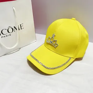 Dettaglio cappello giallo con corona di strass e decorazione in cristallo sulla tesa