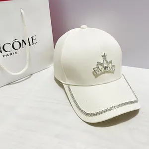 Dettaglio della corona di strass scintillanti su un cappellino in cotone bianco
