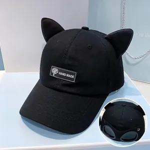 Detail of black baseball cap with cat ears, handmade label and back pilot goggles