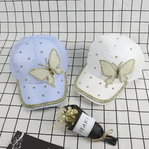 Detail of baseball caps with pearl butterfly embroidery and sparkling rhinestone accents