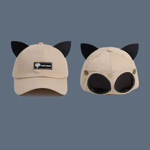 Detail of beige canvas baseball cap featuring cat ears and pilot aviator goggles on back