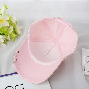 Primer plano de gorra rosa de algodón con elegantes detalles de anillos metálicos