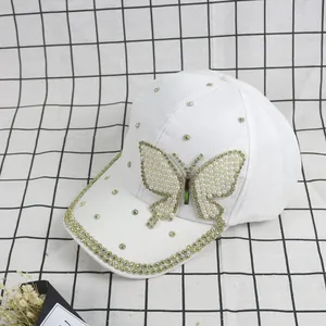 Detail of white baseball cap with pearl and rhinestone butterfly embellishments