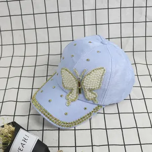 Close-up of light blue baseball cap with pearl butterfly patch and golden rhinestones