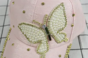 Detailed view of pink cap with pearl butterfly and golden rhinestones