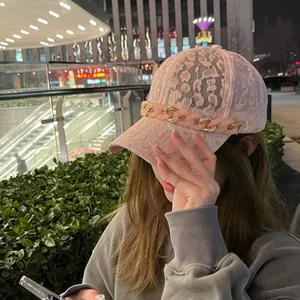 Détail de la casquette rose en dentelle avec chaîne en résine et strass brillants