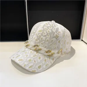 Détail de la casquette en dentelle blanche avec imprimé léopard doré et chaîne cristal