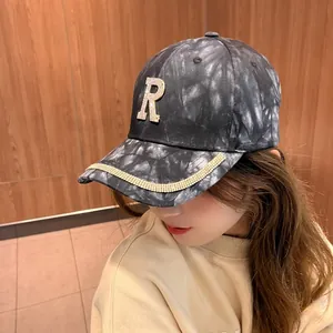 Gros plan sur le logo R en strass de la casquette tie-dye avec bordure en cristal
