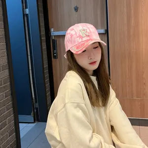 Détail de casquette de baseball tie-dye rose avec logo R en strass et bordure brillante