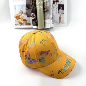 Dettaglio del cappello giallo in cotone con farfalla laser e stampa di lettere