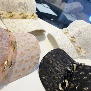 Détail de casquettes en dentelle léopard avec chaîne épaisse et strass brillants