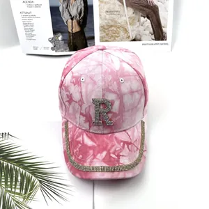 Gros plan sur casquette tie-dye rose avec logo R en strass et bordure scintillante