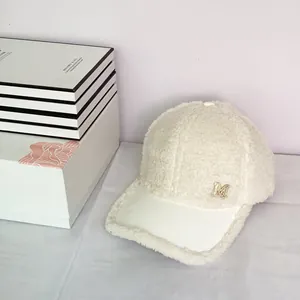 Close-up of white fleece baseball cap featuring a gold rhinestone M logo detail