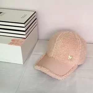 Close-up of pink faux shearling texture and metal M logo on the winter baseball cap