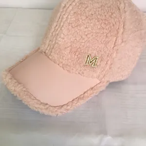 Close-up of pink fleece baseball cap with leather brim and crystal M metal logo
