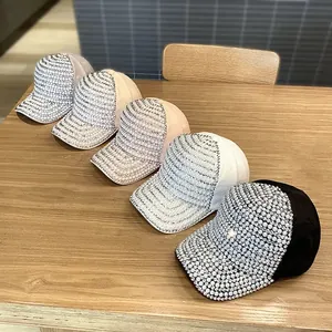 Detail view of five fashion baseball caps with rhinestones and pearls on a wood surface