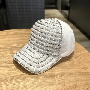 Close-up of white baseball cap with densely decorated faux pearls and sparkling rhinestones