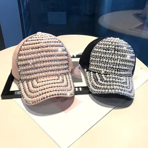 Close-up of luxury rhinestone and pearl embellishments on pink and black baseball caps