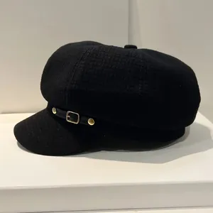Detail van de zwarte geruite baret met leren riempje en gouden metalen gesp decoratie