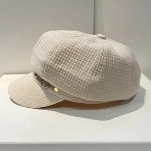 Detail van lichtbeige newsboy pet met wafelstructuur en leren riempje decoratie