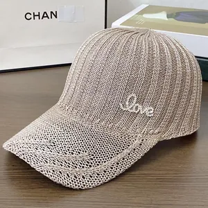 Détail de la texture tricotée et des lettres LOVE en strass sur la casquette beige