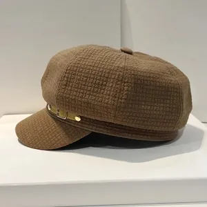 Detailopname van de donkerbruine baret met textuur en metalen gesp-accenten op de stof
