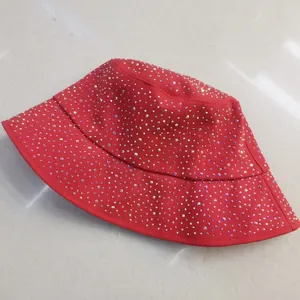 Détail d'un chapeau cloche rouge en coton orné de strass brillants sur le large bord